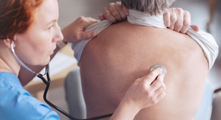 Nurse with patient using stethoscope on patients back